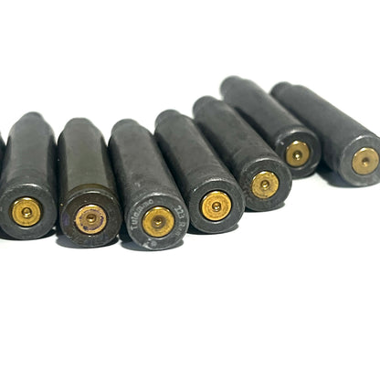 Row of gray steel .223/5.56 spent casings viewed from base showing primer pockets, on white background