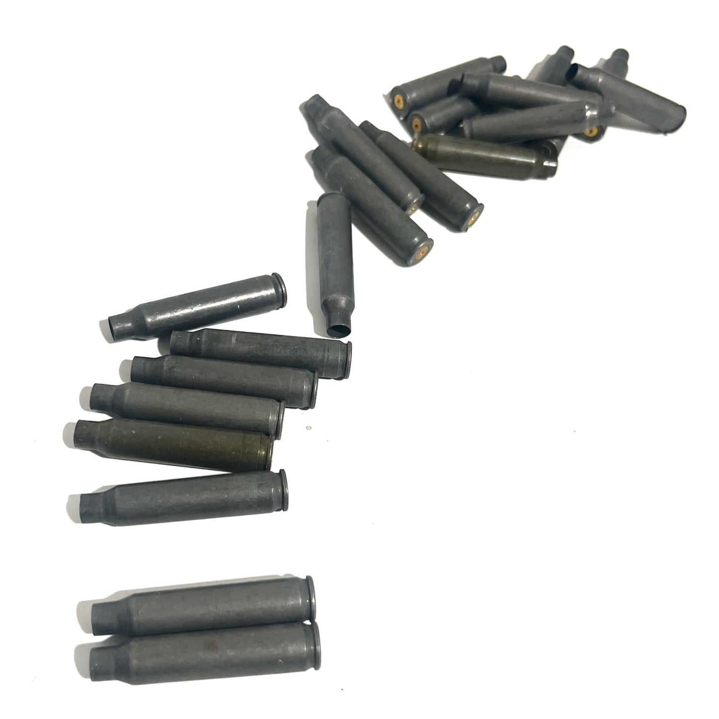 Gray steel .223/5.56 spent casings scattered on white background in loose rows, one standing upright