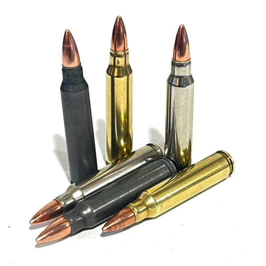 Six .223/5.56 casings in black, brass, and silver finishes, three dummy rounds standing and three fanned in front.