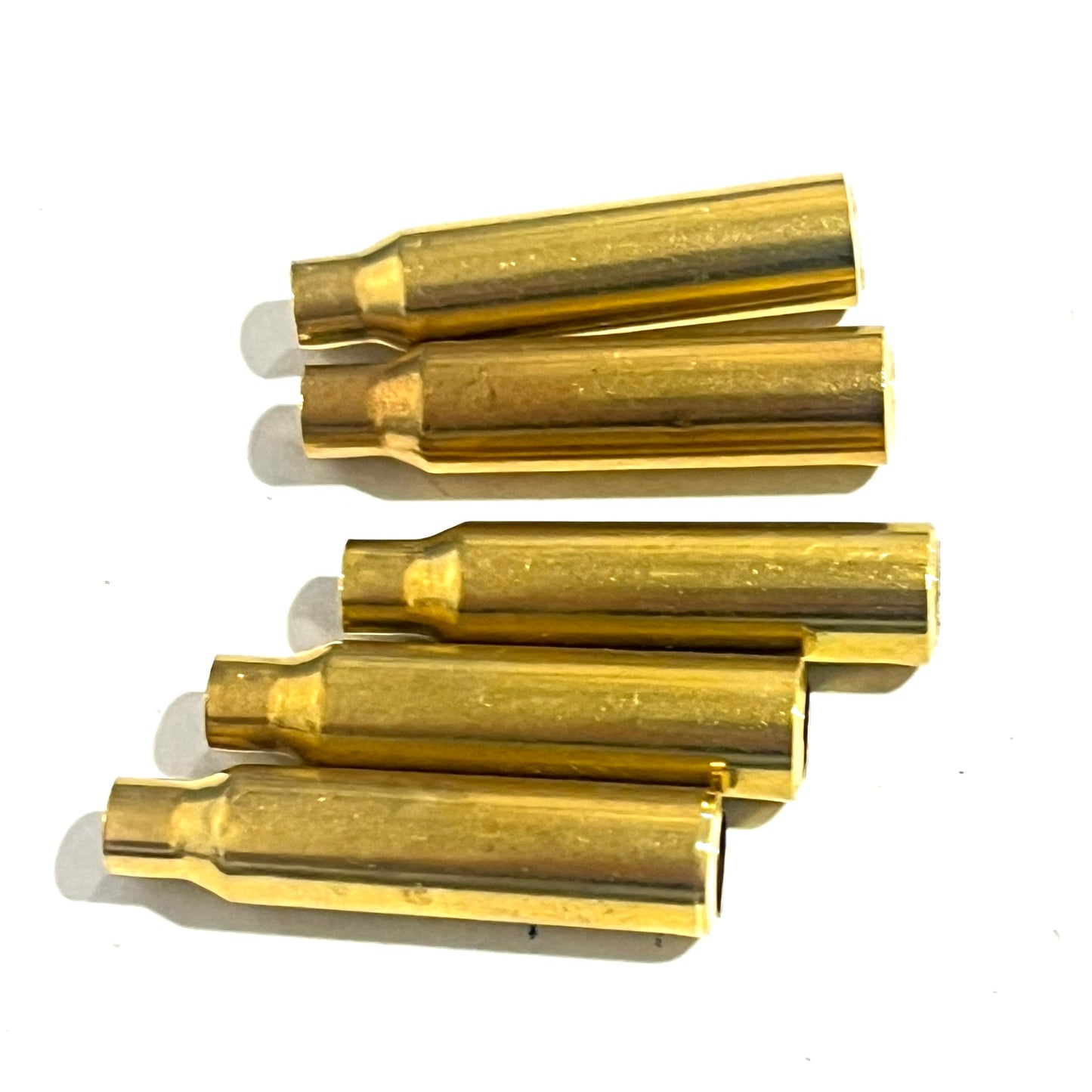 Five .223 brass bullet casing beads lying on their sides showing the tapered case body