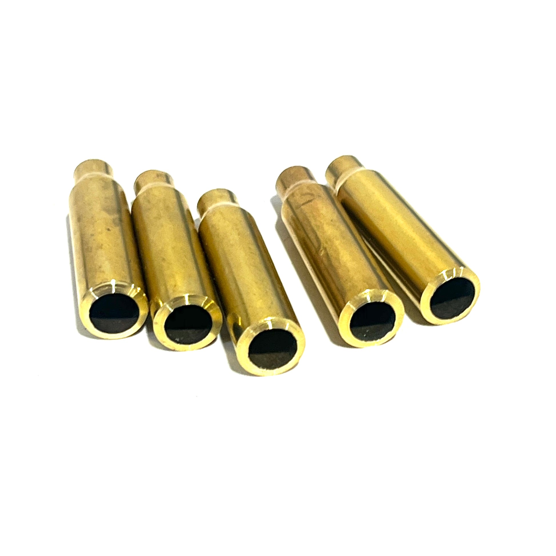 Five .223 brass bullet casing beads standing upright showing the open black interior at the cut end