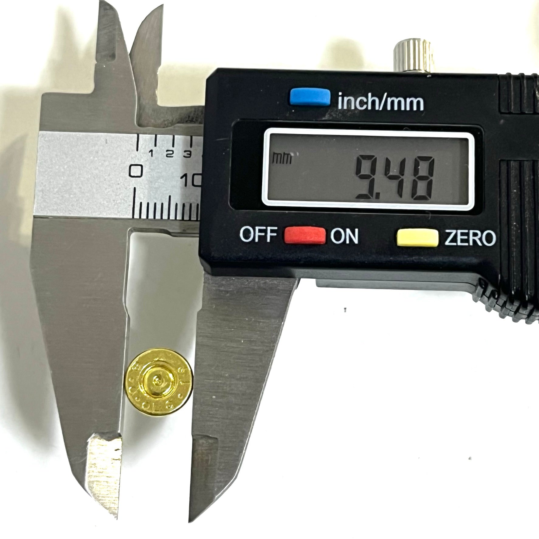 A single polished brass .223 bullet slice held in digital calipers showing a diameter of 9.48 millimeters.