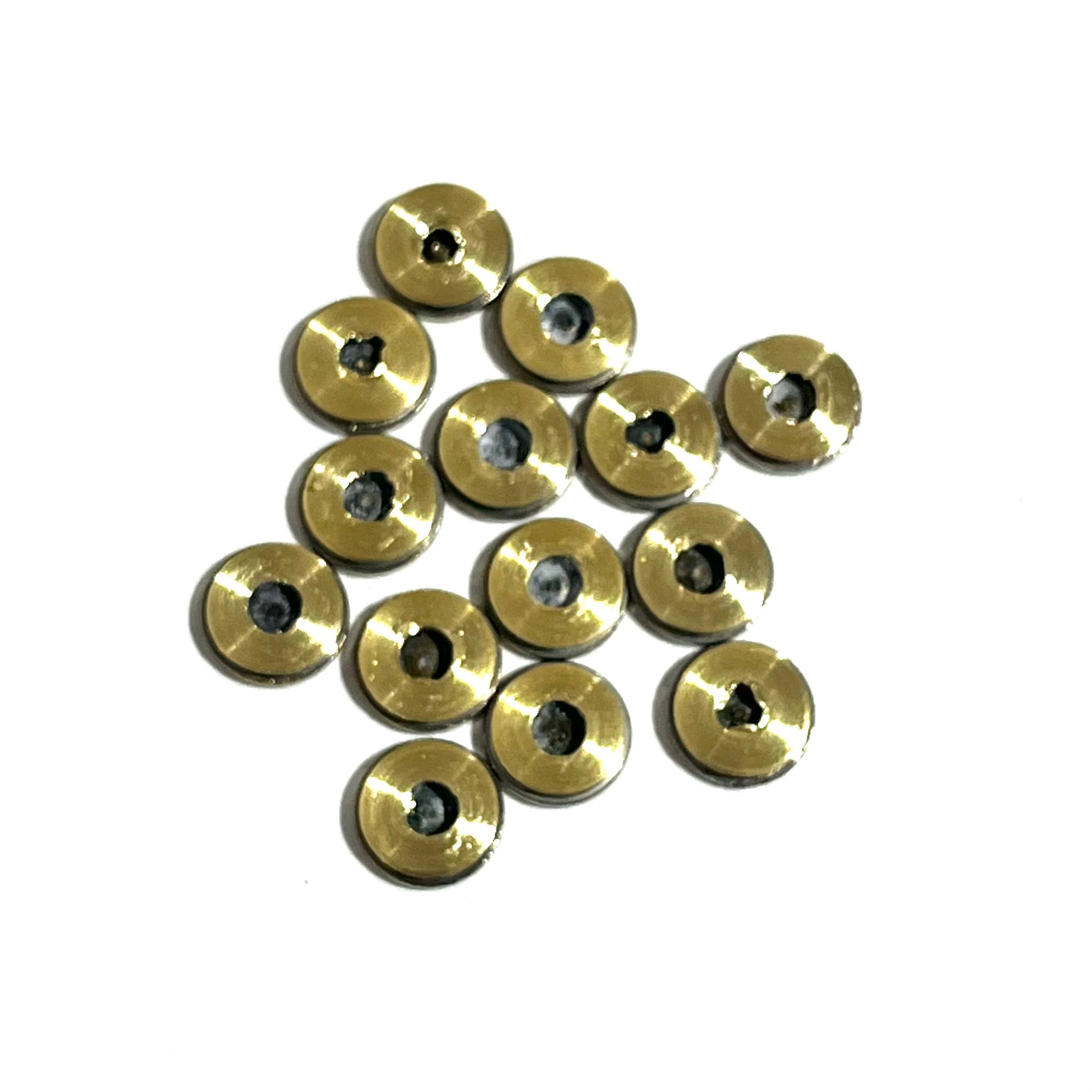 Thirteen brass 223 5.56 bullet slices showing the drilled bullet side on a white background