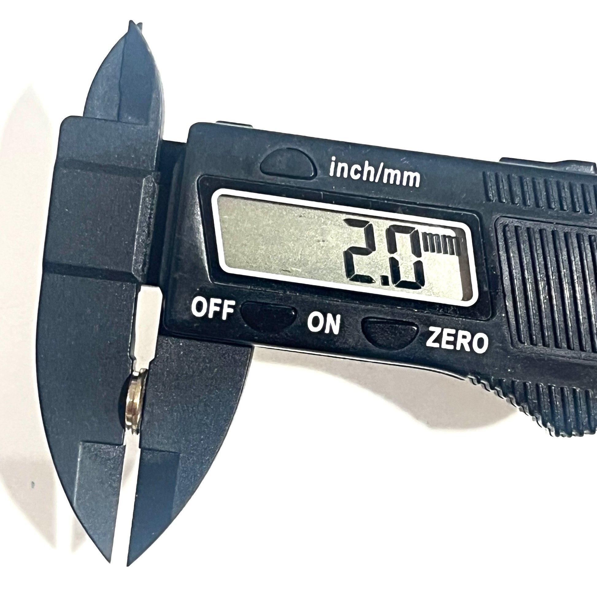 An empty nickel hull slice held in caliper jaws, measuring 2.0 mm thick against a white background.