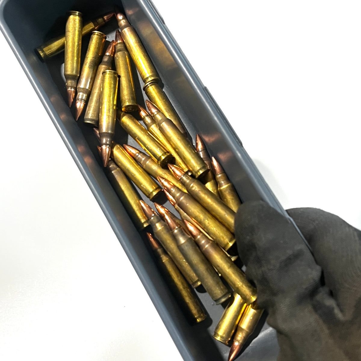 Dirty .223 dummy rifle rounds held in a metal tray by a gloved hand for props