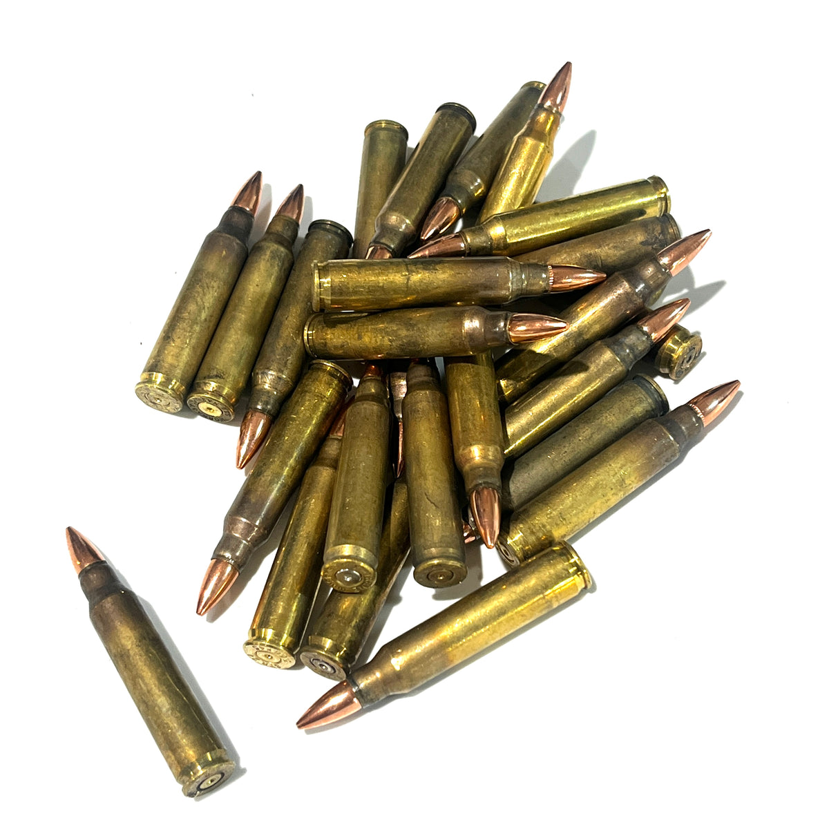 A pile of dirty .223 fake dummy cartridges with one set apart on white background