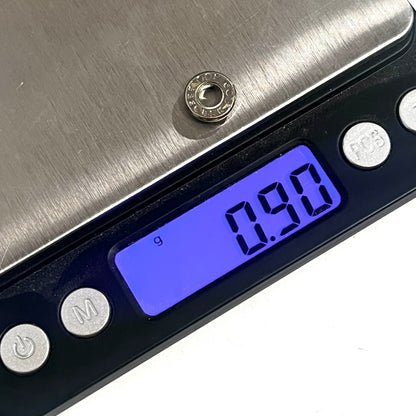 A used nickel 223 bullet slice resting on a digital scale that reads 0.90 grams.