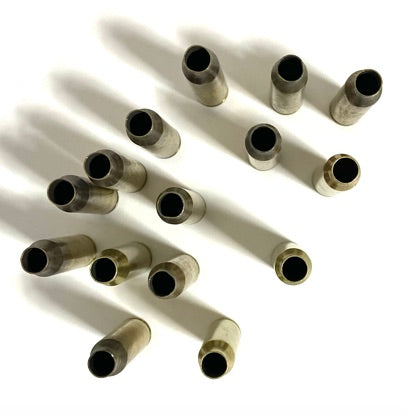High-angle view of ten raw 223 rifle brass casings standing upright on white background with open top mouths