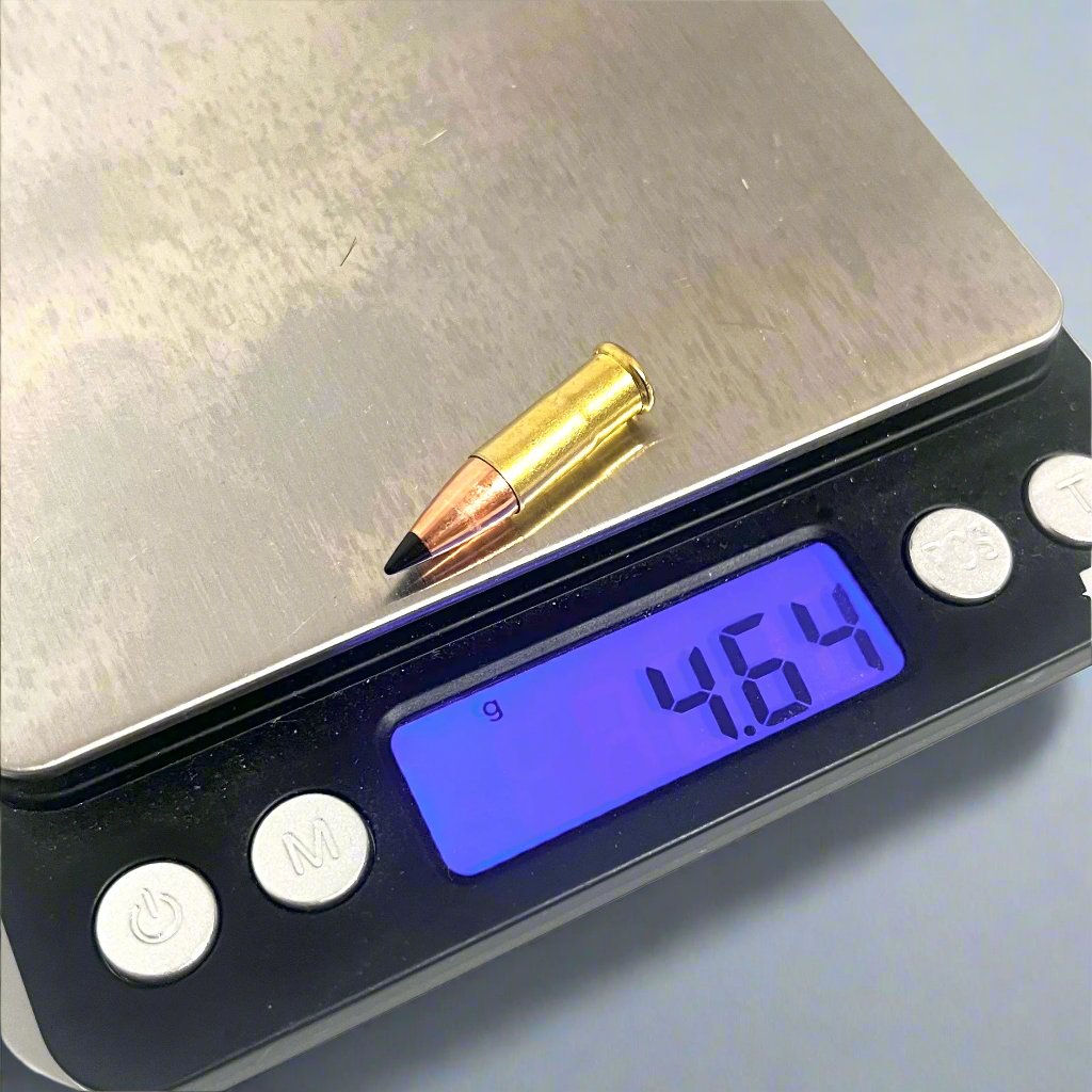 .22 caliber dummy round with a black polymer bullet tip on a digital scale reading 4.64 grams