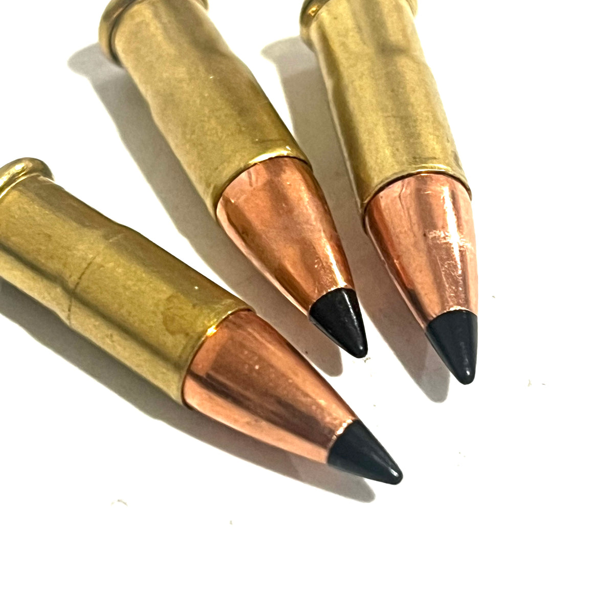 3 .22 caliber dummy rounds with black polymer bullet tips, lying on a white background