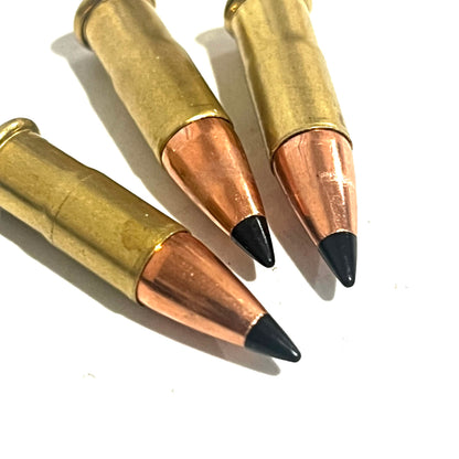 3 .22 caliber dummy rounds with black polymer bullet tips, lying on a white background
