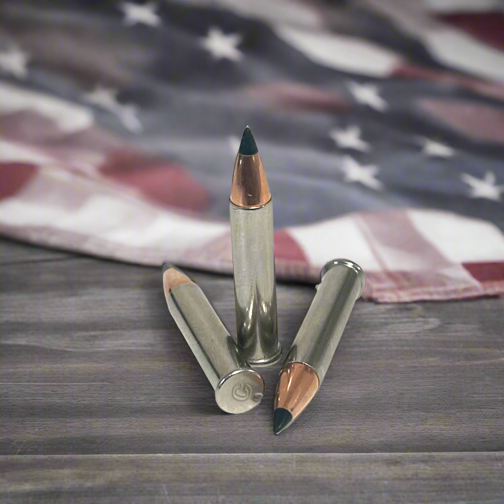 3 .22 Magnum nickel dummy rounds with black polymer tipped bullets, standing and laid on weathered wood in front of blurred American flag