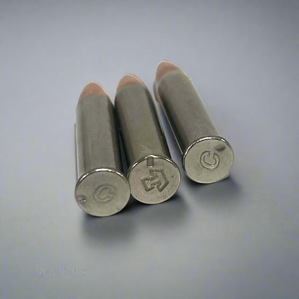3 .22 Magnum nickel dummy round bases viewed from above showing headstamp markings, gray background