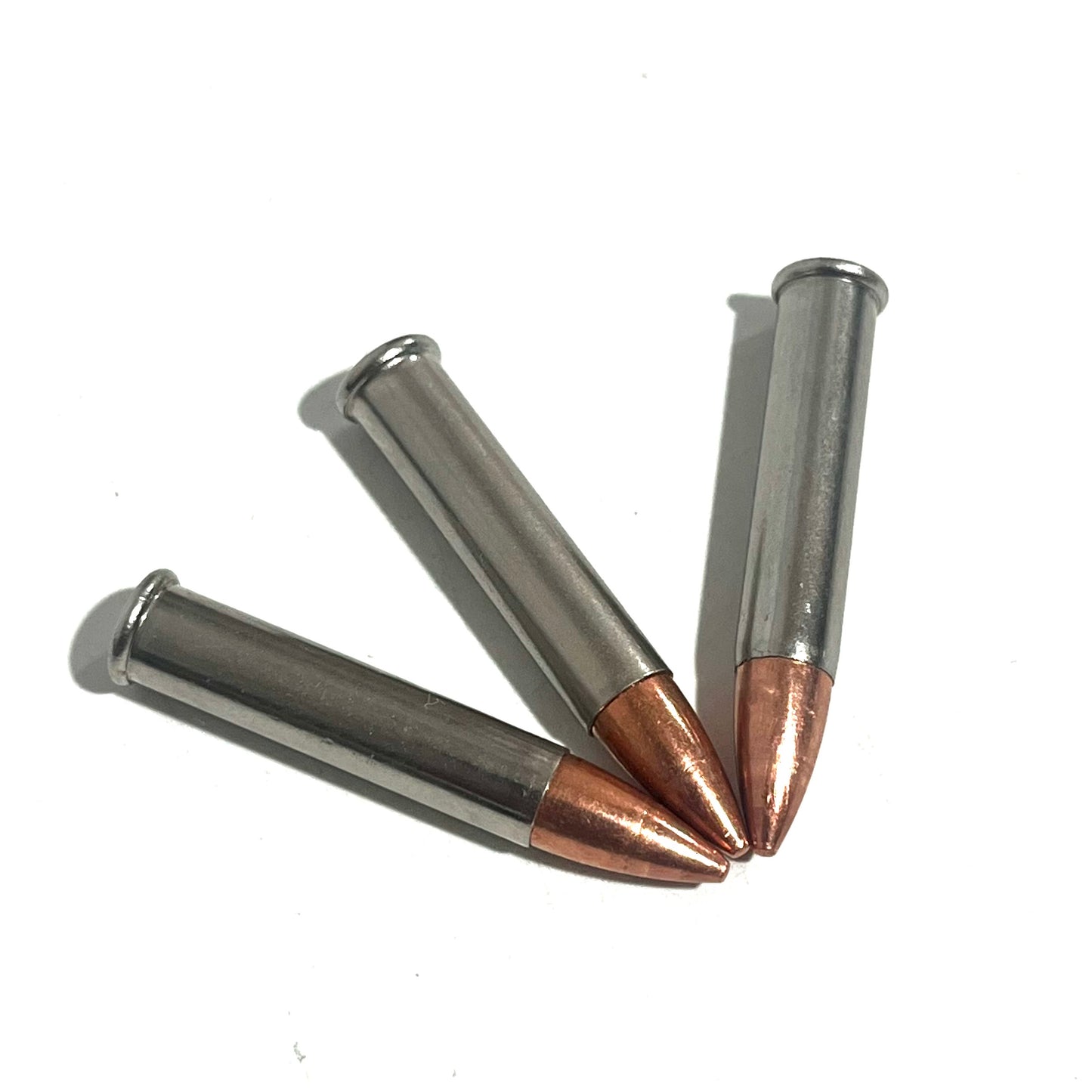 3 .22 Magnum nickel dummy rounds fanned out on white background, copper bullet tips