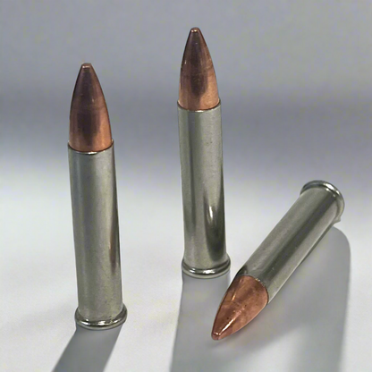 3 .22 Magnum nickel dummy rounds with copper bullets standing on a wood slice, blurred rustic background