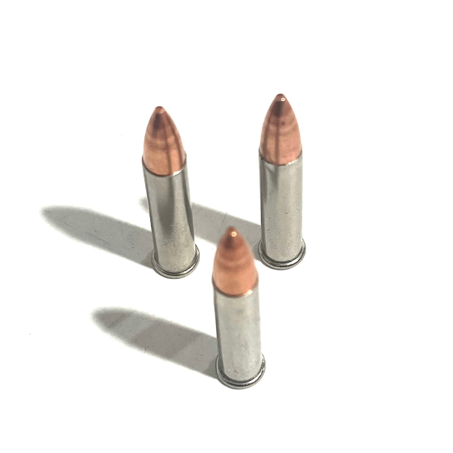 3 .22 Magnum nickel dummy rounds standing upright with copper bullets on white background