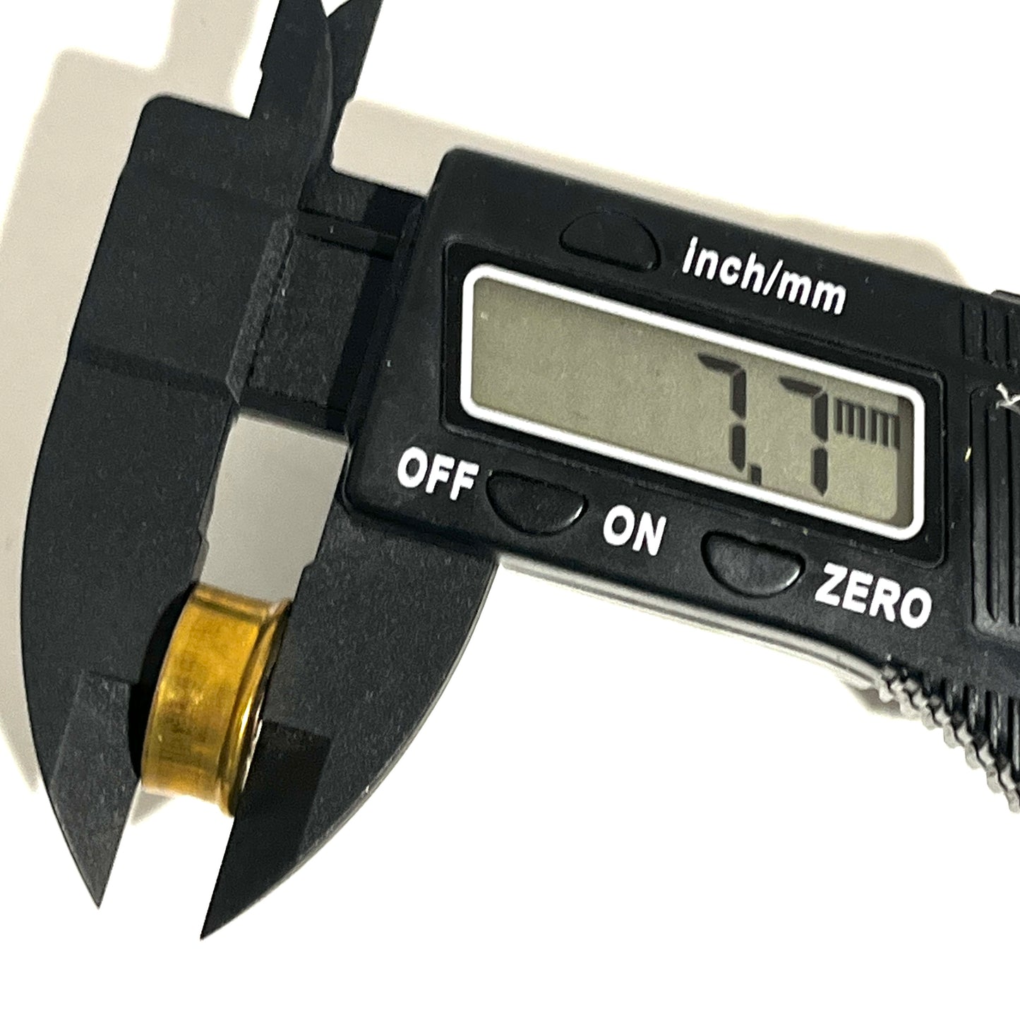 Digital caliper measuring the side height of a gold brass 28 gauge headstamp slice showing 7.7 mm on the display.