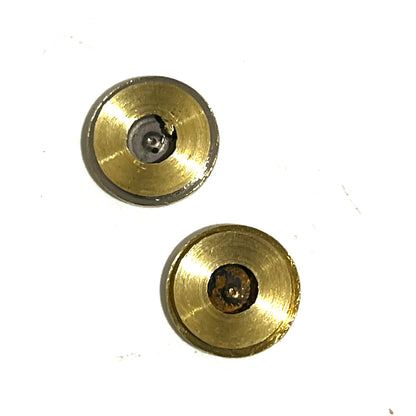 2 round brass bullet slices with tarnished centers viewed from the primer side
