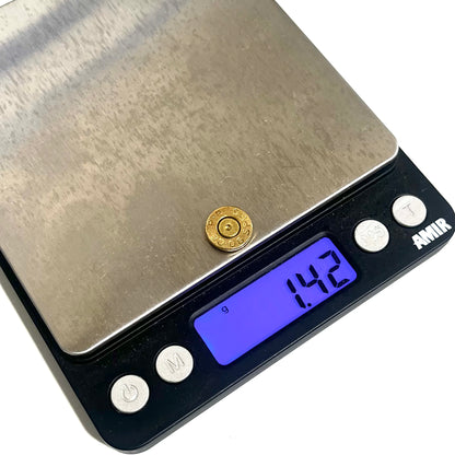 A gold brass bullet slice on a digital gram scale showing 1.42 grams