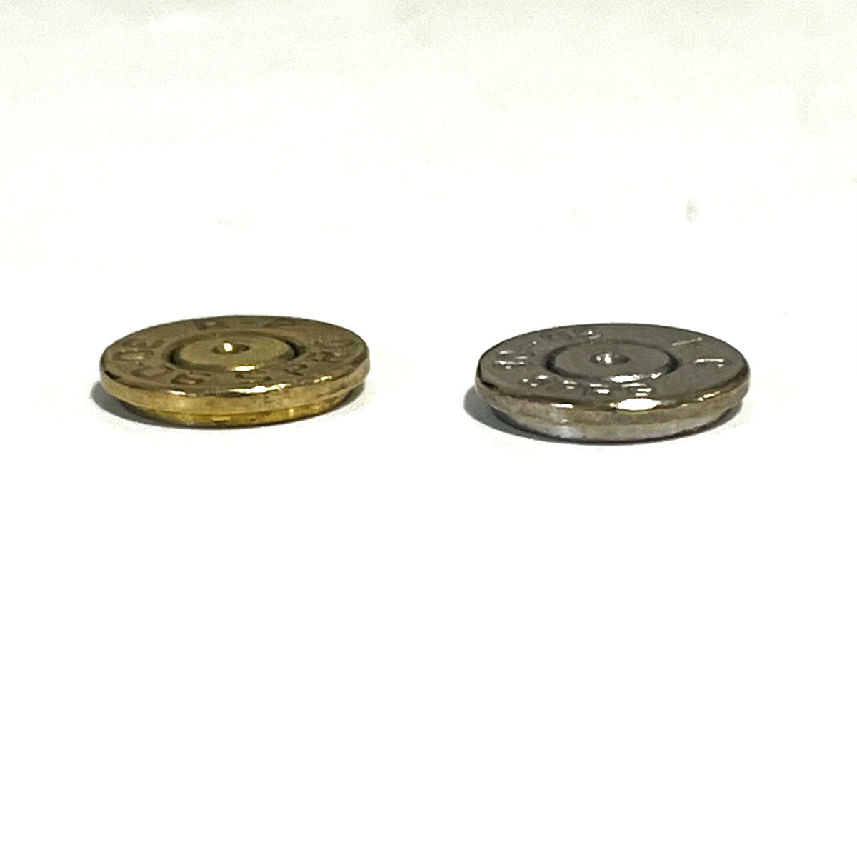 2 round bullet slices, one brass and one nickel, lying side by side on a white background