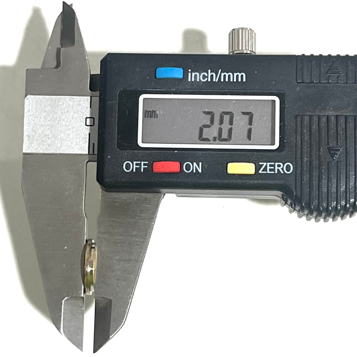 Digital caliper measuring the thickness of a bullet slice showing 2.07 mm