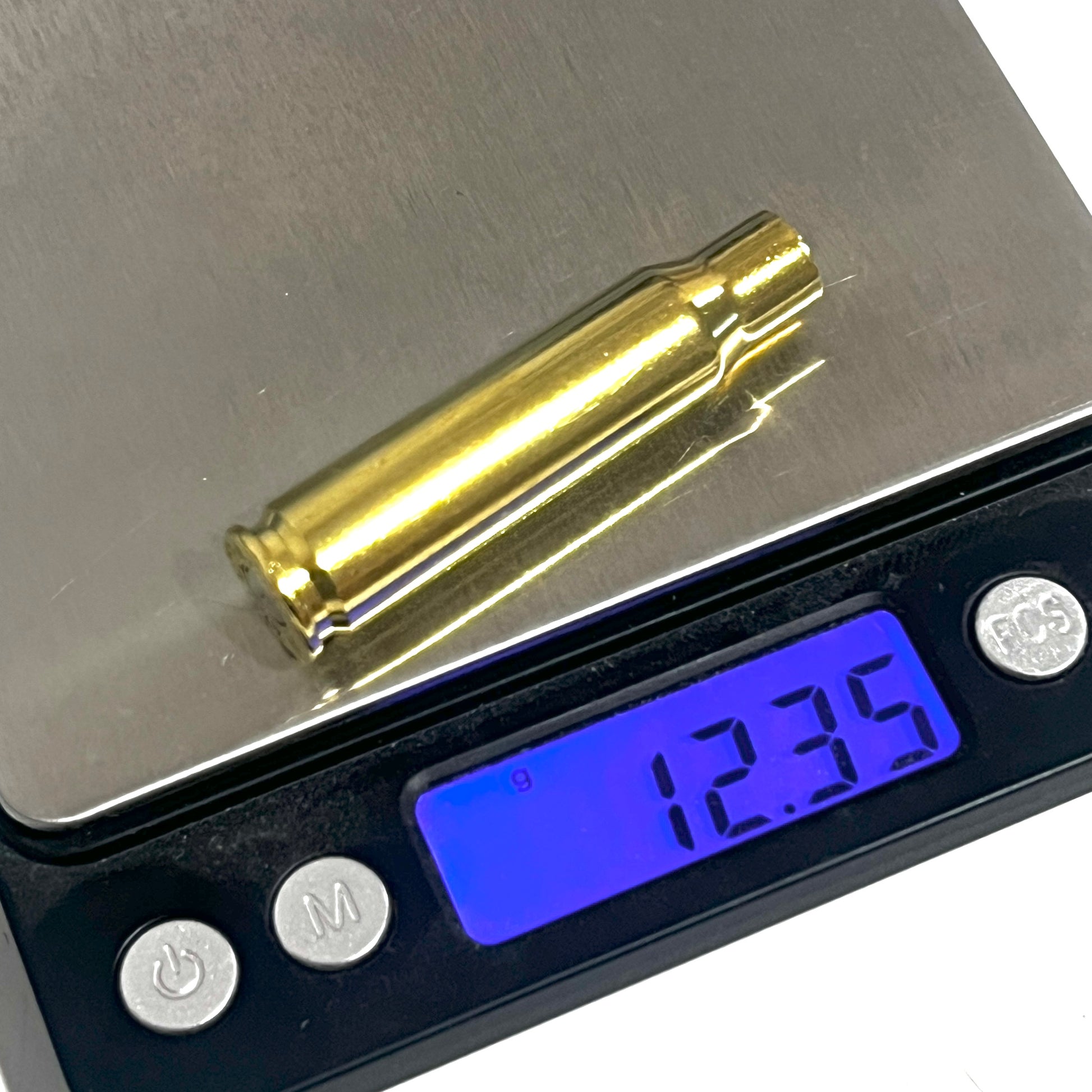Single gold 308 WIN brass cartridge case resting on a digital scale displaying a weight of 12.35 grams.