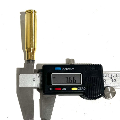 Digital caliper measuring the neck diameter of a gold 308 WIN brass shell, showing a readout of 7.66 mm.