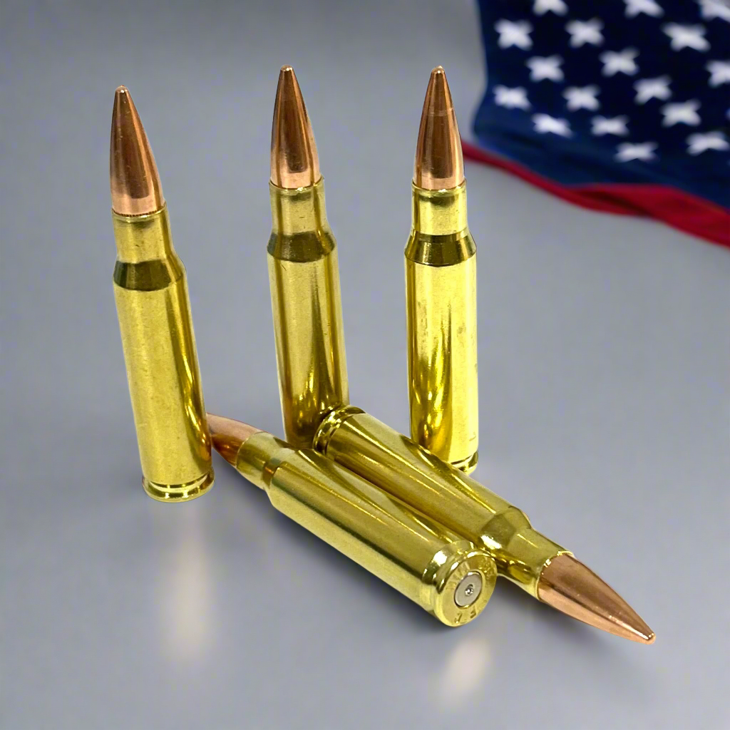 Five brass .308 prop fake rounds with copper tips, three upright and two lying flat, American flag blurred behind