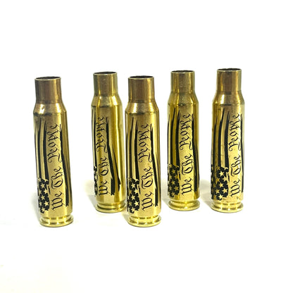Five upright .308 WIN brass casings engraved with a We The People flag script design, arranged side-by-side.