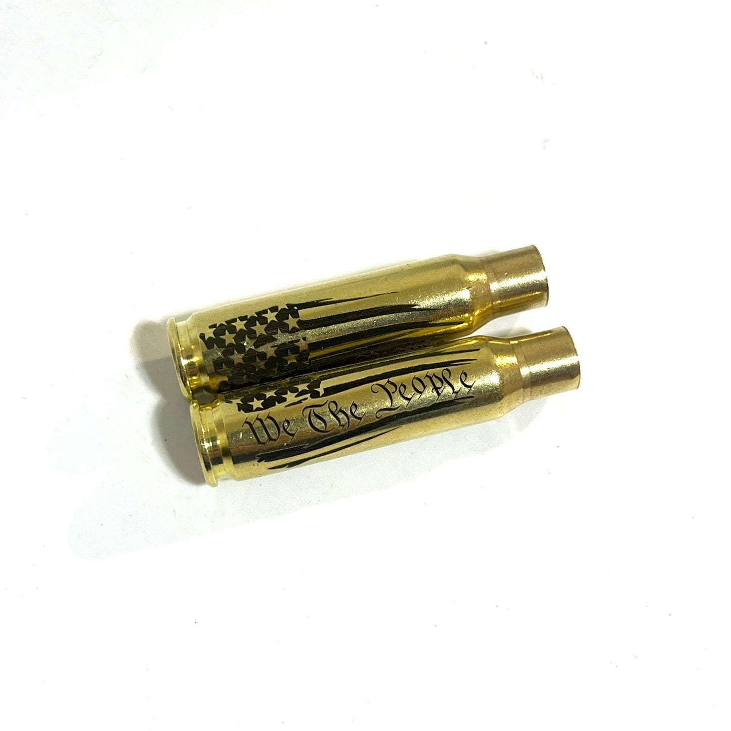 Two horizontal .308 WIN brass shells engraved with the We The People flag pattern, isolated on a white background.