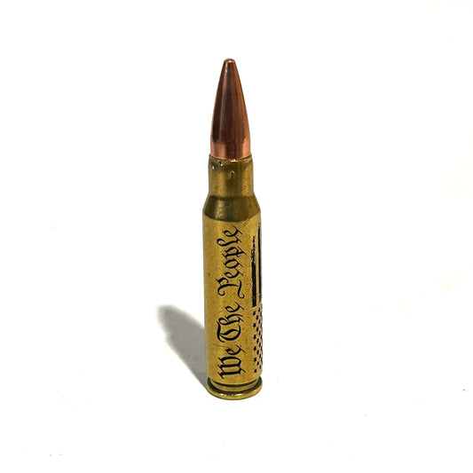 Vertical 308 win dummy round with engraved We The People script and flag on authentic once-fired brass casing.
