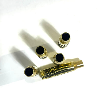 Four upright empty casings showing open mouths clustered around one horizontal .308 WIN engraved case on a white surface.