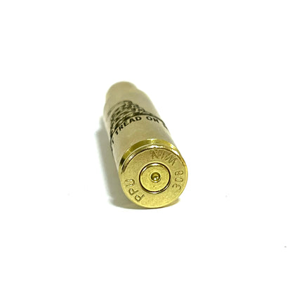 Close up view of a 308 WIN brass cartridge standing upright showing PPU base headstamp and engraved words.