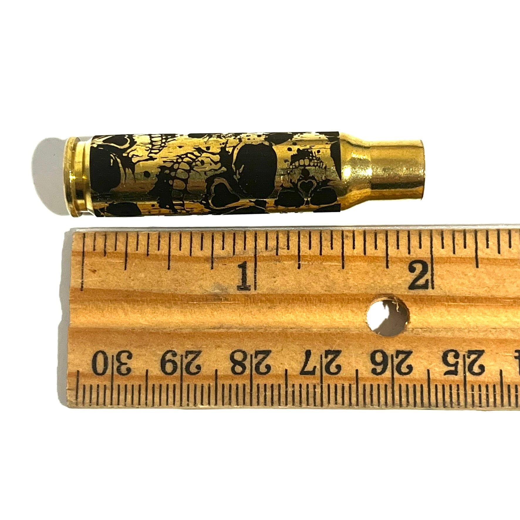 308 WIN laser-engraved brass casing positioned next to a wooden ruler showing a length measurement of 2 inches.