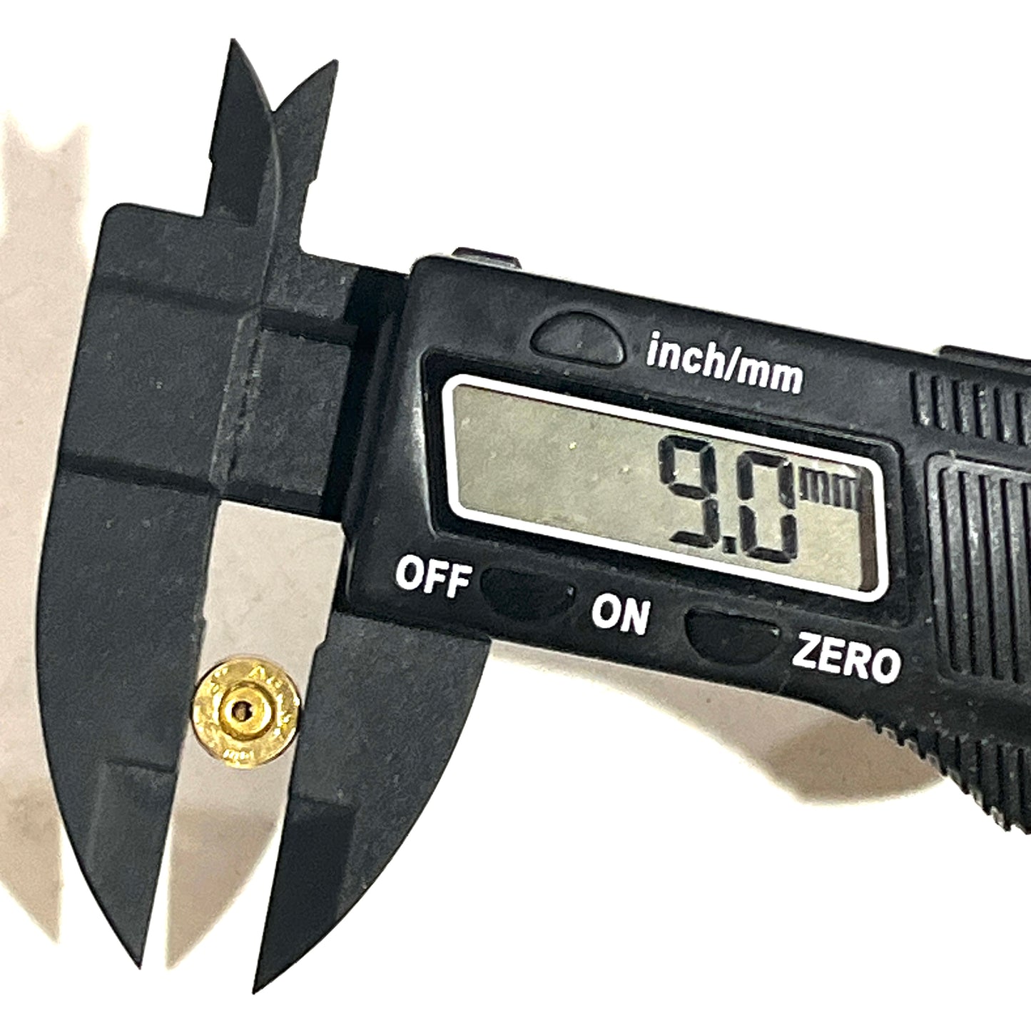 Black digital caliper measuring outer diameter of a .32 Auto brass shell showing 9.0 mm on display.