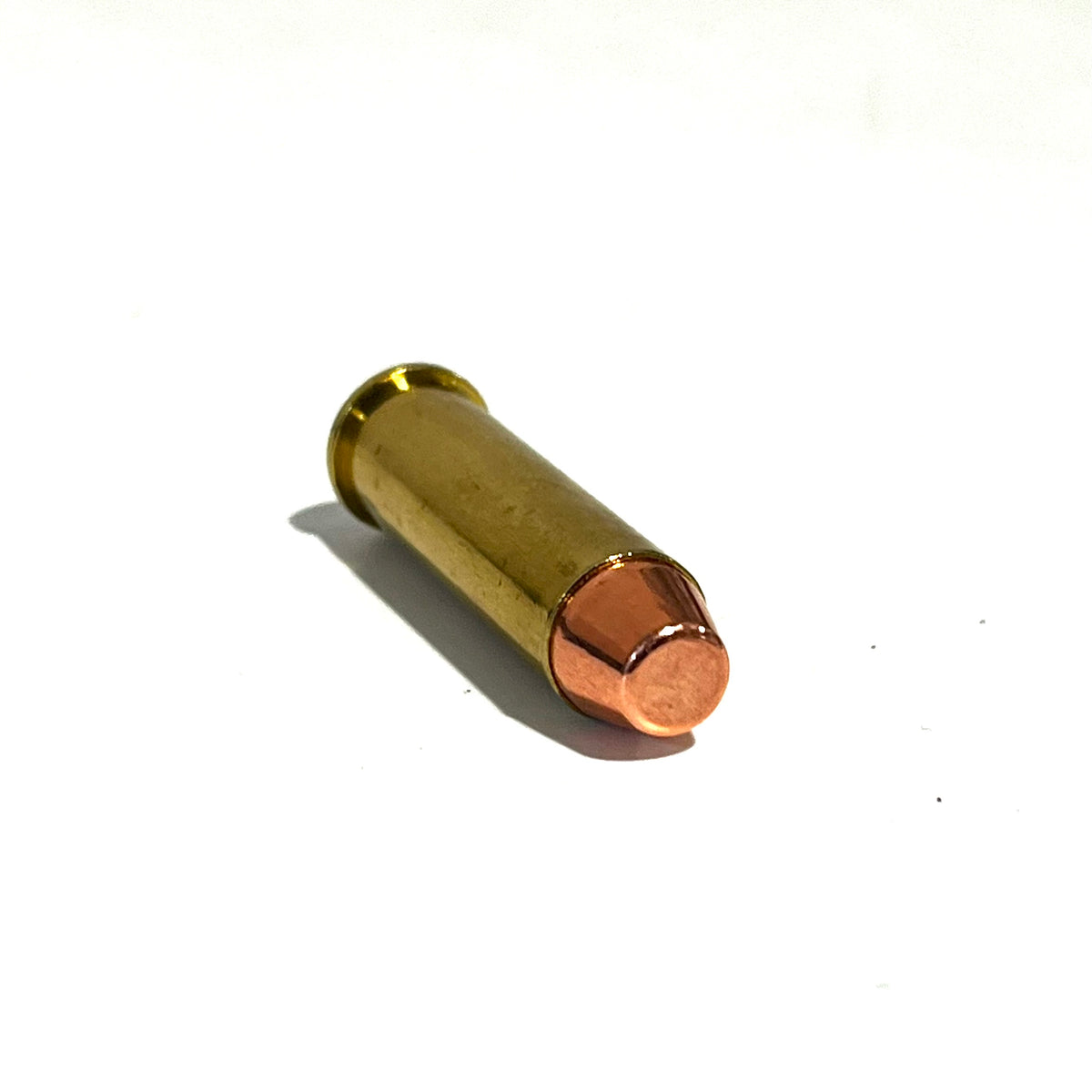 Single 357 Magnum brass dummy round lying on its side on a white background showing the flat-nose bullet