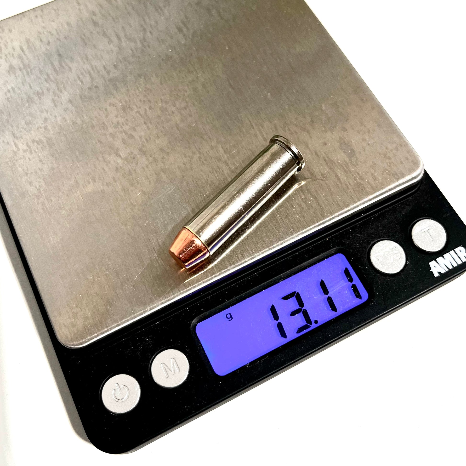 A single nickel 357 Magnum dummy round with  and a copper flat nose bullet on a digital scale showing a weight of 13.11 grams.