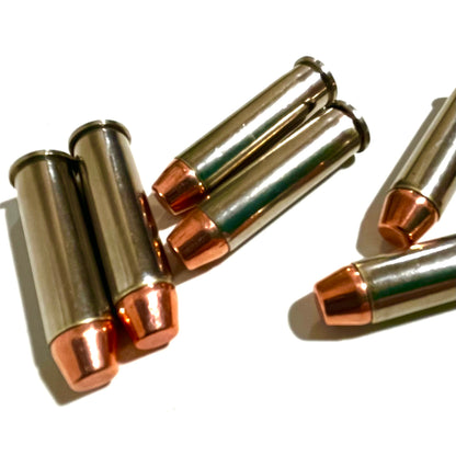 Five nickel dummy rounds with copper flat nose bullets clustered together on a clean white surface with distinct shadows.