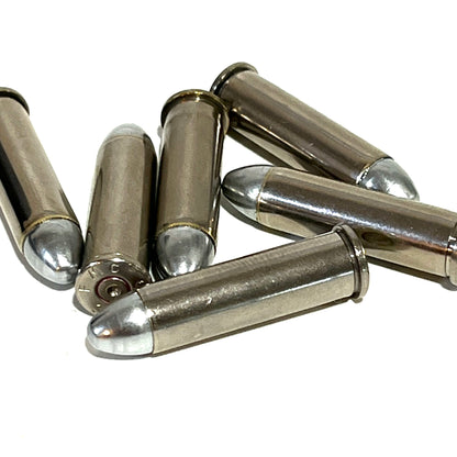 Six nickel 357 Magnum dummy rounds with round nose bullets lying on a white background