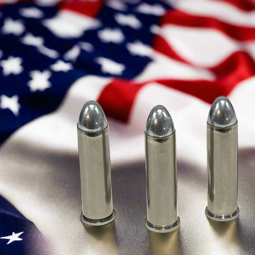 Three nickel 357 Magnum dummy rounds with round nose bullets standing on an American flag background