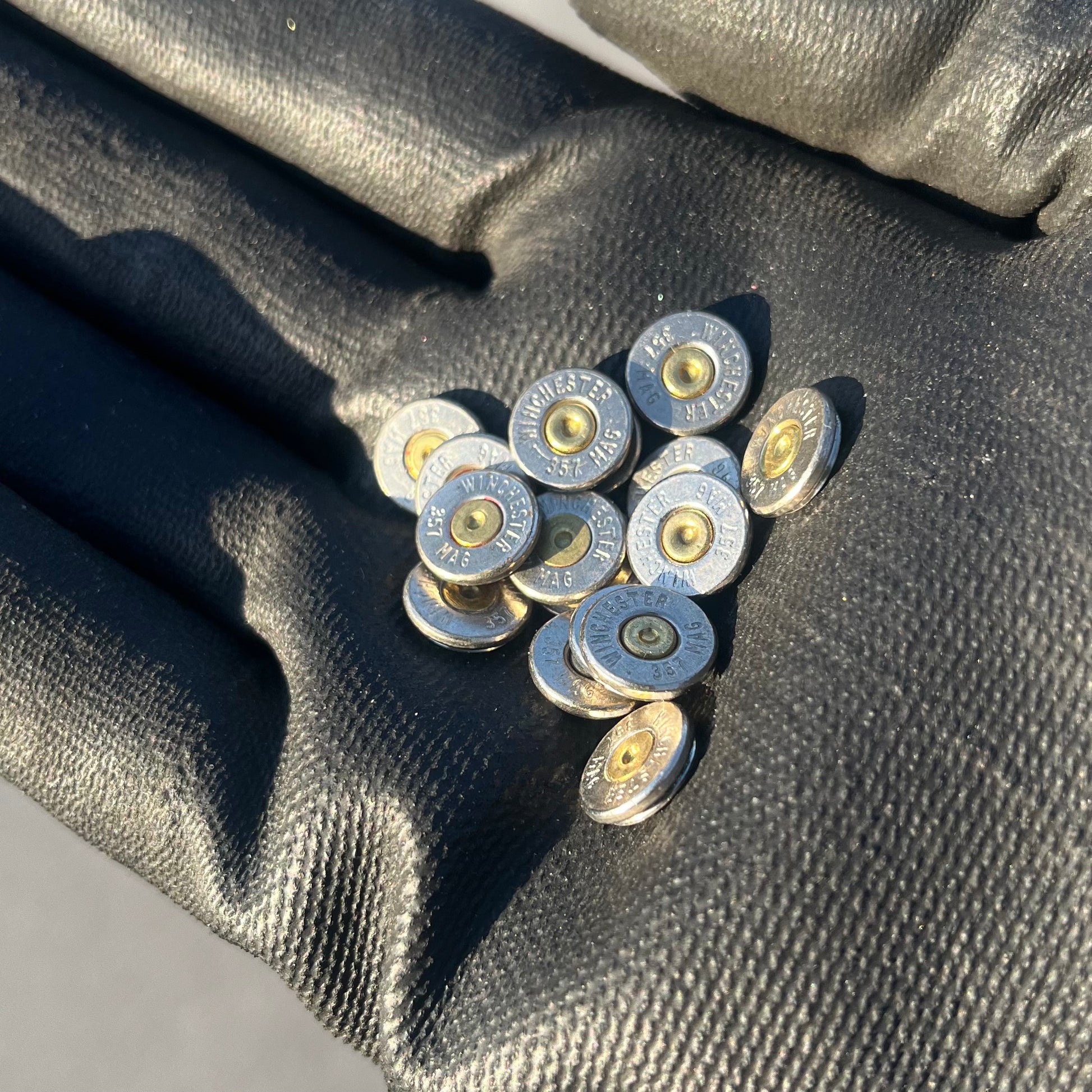 A small pile of 357 Magnum nickel bullet slices resting on a black glove