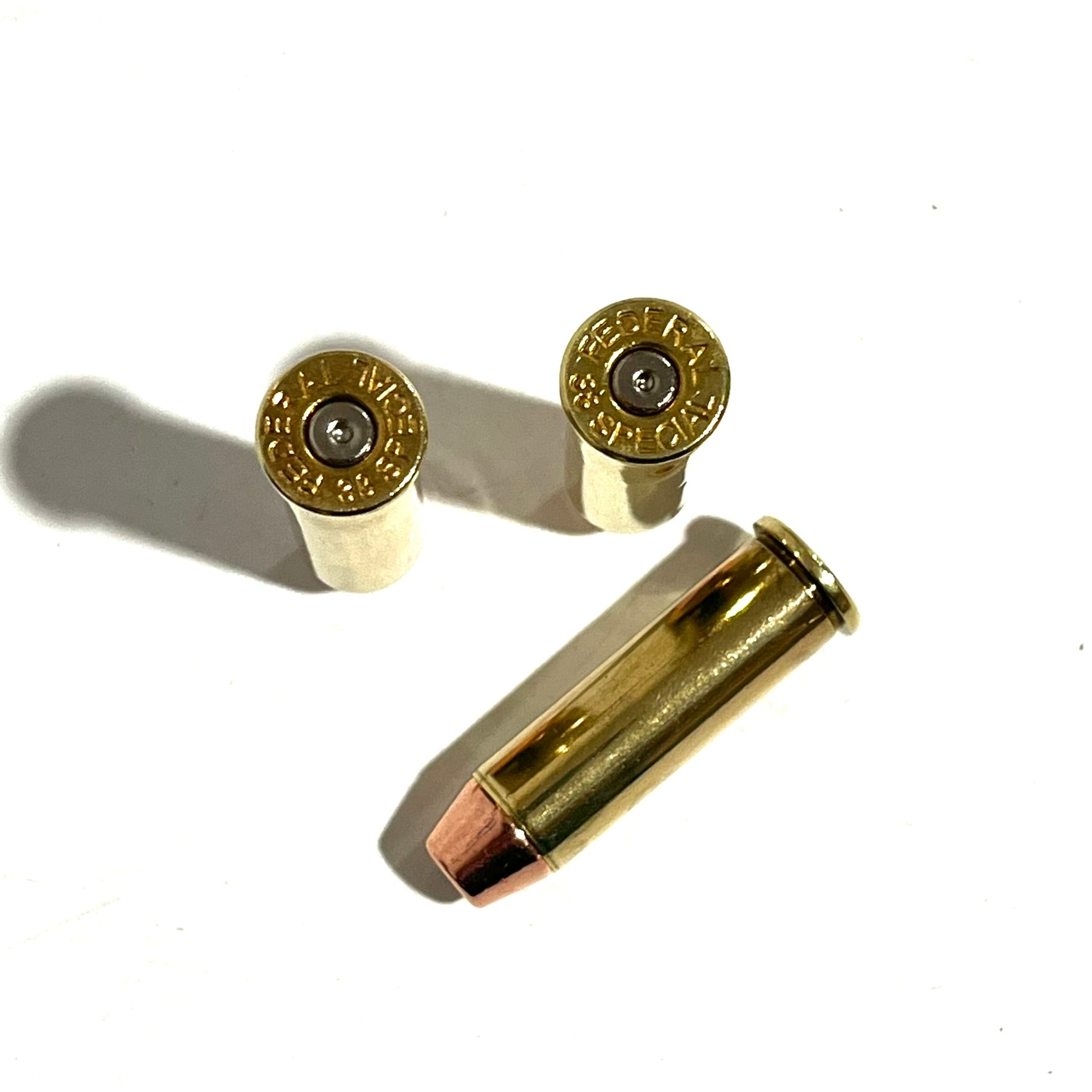 Two .38 Special brass dummy rounds laying flat and angled slightly away from each other on a white background.