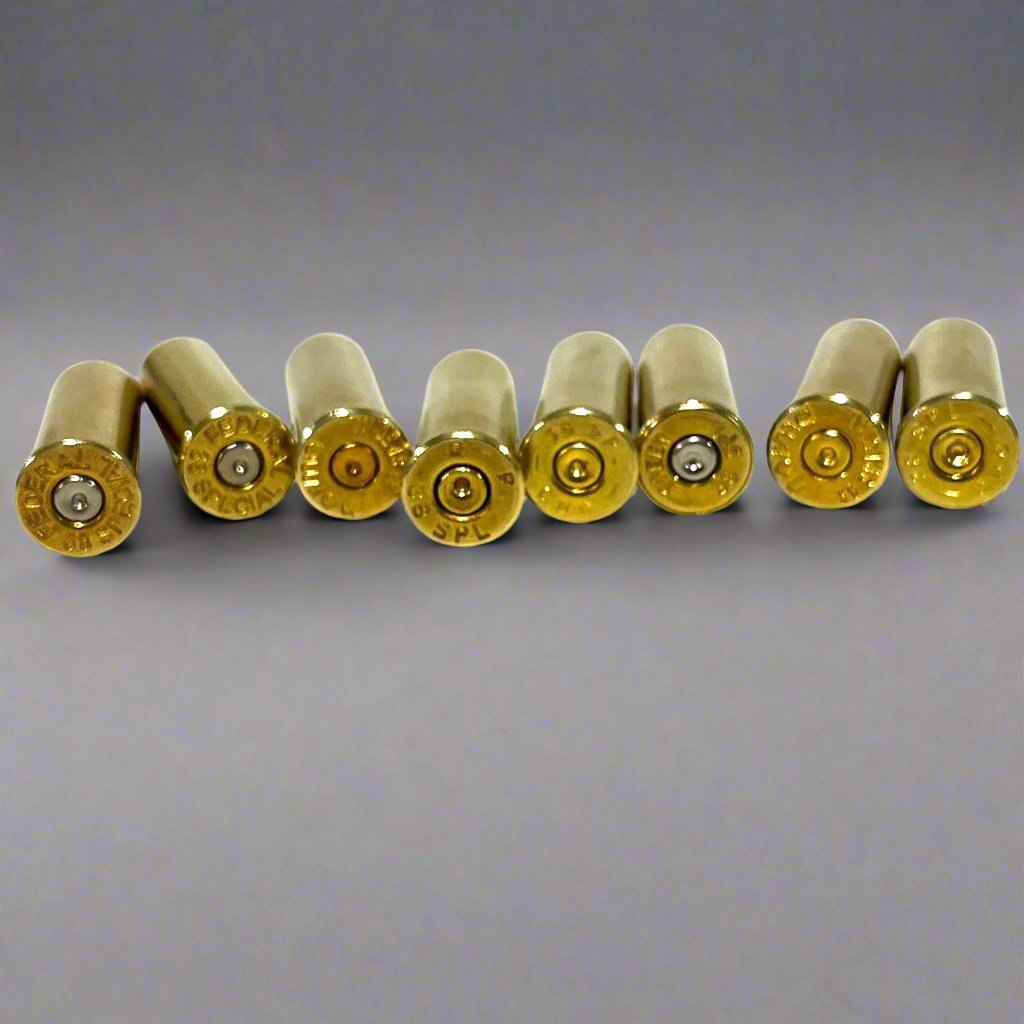 8 pcs .38 Special brass prop rounds arranged in a straight horizontal line on a white surface.