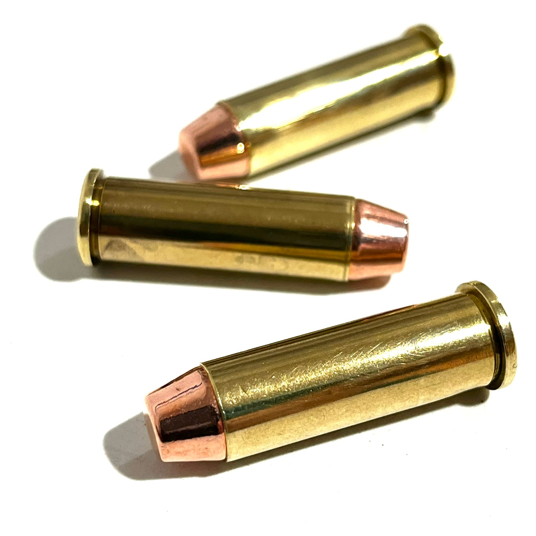 Three .38 Special brass dummy rounds stacked diagonally on top of each other against a white background.