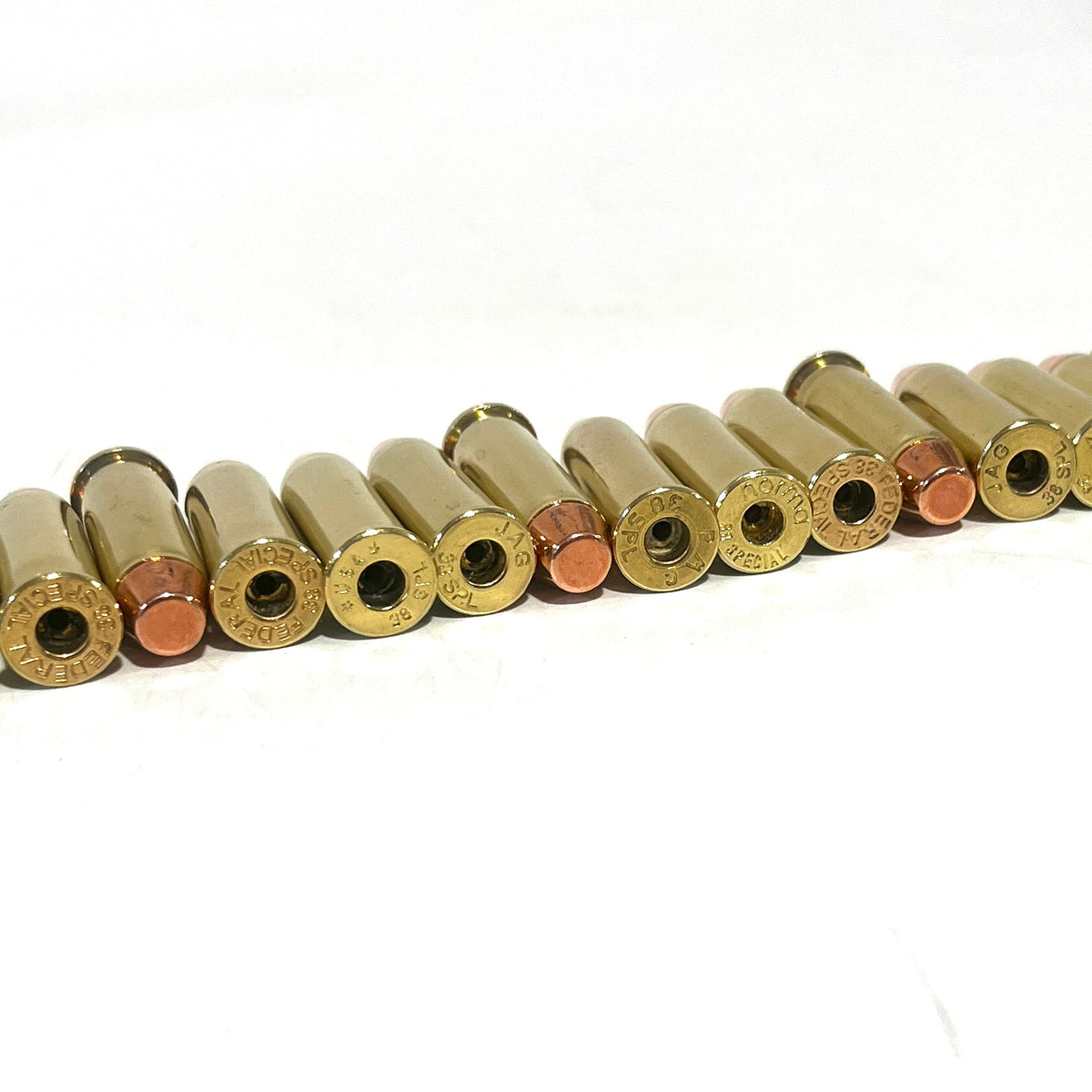 12 brass 38 Special deprimed cases with empty primer pockets, lying in a row viewed from the base