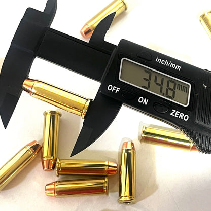 Digital caliper measuring a brass 38 Special dummy round's length at 34.8 millimeters, with more rounds scattered nearby