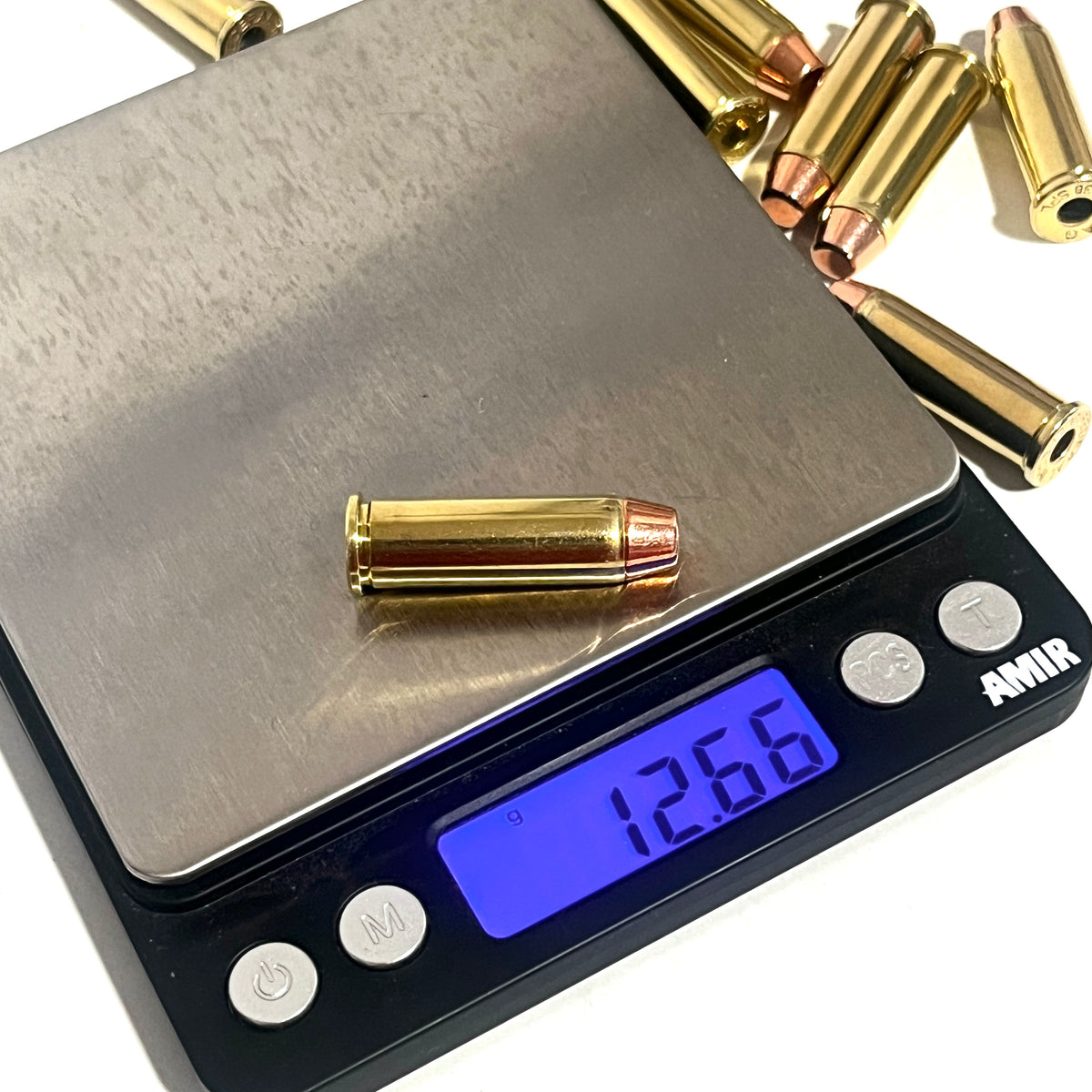Brass 38 Special dummy round with a flat nose bullet on a digital scale reading 12.66 grams, with more rounds in the background