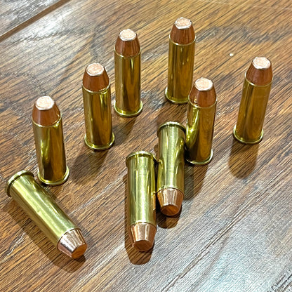 Nine .38 Special brass dummy rounds with flat-nose bullets scattered naturally across a rustic wooden table surface.