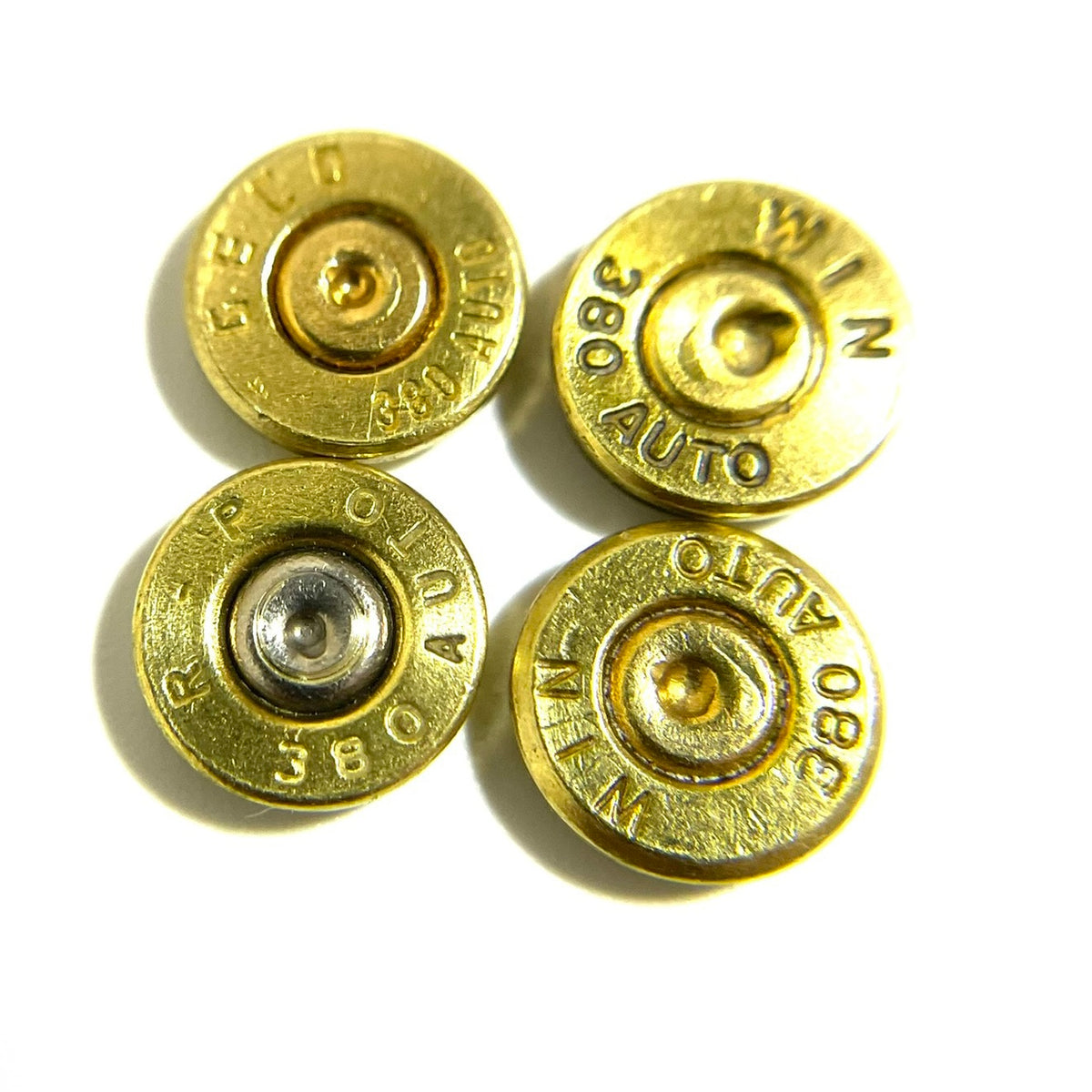 Four gold brass 380 Auto bullet slices with Federal and Winchester headstamps on a white background
