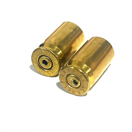 2 gold .380 caliber brass shell casings lying on their sides, headstamps facing forward